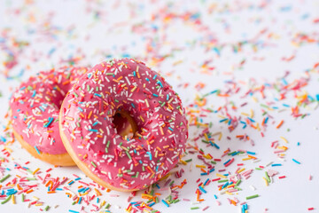 Delicious dessert. Pink donut with multicolored sprinkles on a white background of Sweets. Confectionery products.