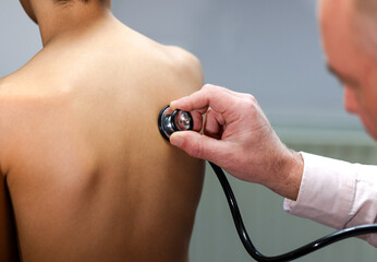 Fototapeta premium Closeup hand of Caucasian male pediatrician use stethoscope do pediatric checkup examination on child boy patient from back to check heart lungs, children medical care concept. 