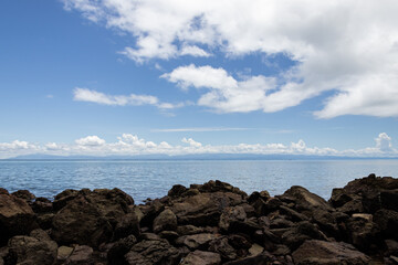 Morning sky and sea, clear white clouds, daytime, relaxing feel, copy space, rocks in front, suitable for background.