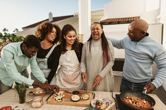 Happy African family preparing food recipe together on house patio