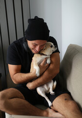 stylish guy, teenager, dressed in black clothes, black hat. the guy is at home with his chihuahua dog, friends hugging, playing, spending time together, the dog is the guy's best friend. comfortable 