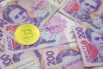 Golden bitcoin on two hundred ukrainian hryvnia bills background