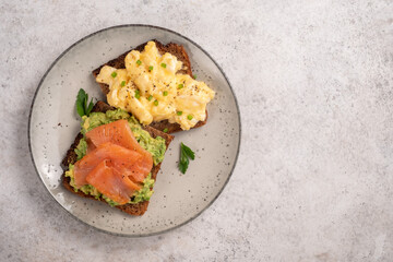 Scrambled eggs with smoked salmon and avocado on a whole wheat toast
