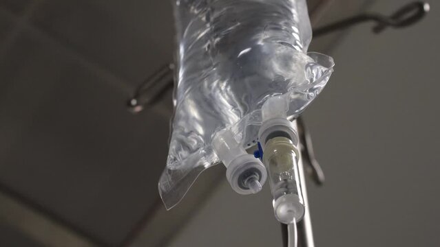4K close-up IV drip dropper stock video. Operating room footage during real surgery. Swift dribbling liquid.