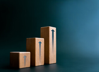 Rise up arrow on wooden cube blocks, bar graph chart steps on dark blue background with copy space,...