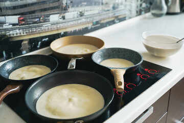 Russia Moscow 14.03.2021 Cooking many big tasty pancakes Lot of pans,oil,pancake dough.Russian traditional national festival winter Maslenitsa holiday week,shrovetide. Man, father cook.Family holiday