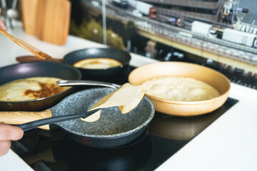 Russia Moscow 14.03.2021 Cooking many big tasty pancakes Lot of pans,oil,pancake dough.Russian traditional national festival winter Maslenitsa holiday week,shrovetide. Man, father cook.Family holiday
