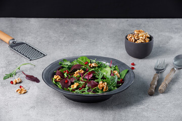 Salad mix with fresh spinach, walnuts, pomegranate on a stone table.