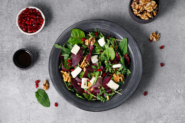 Top view salad mix with fresh spinach, walnuts, pomegranate and white cheese on a stone table.