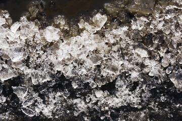 Snow background. Ice texture. Winter seanson pattern. Pile of snow. Crystal snowflake shine. Frozen puddle. Small pieces of ice. Cracked water freeze.