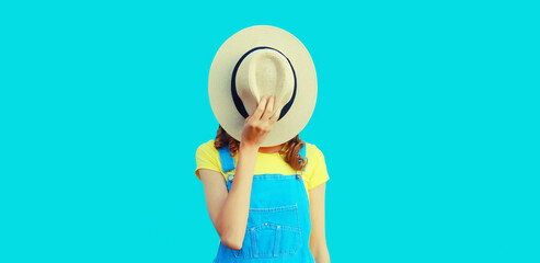 Portrait of unknown stranger young woman covering her face with summer straw round hat on blue background