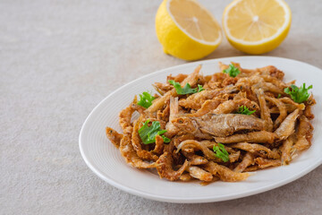 Crispy fried small fish on white plate