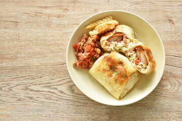 burrito Mexican food stuffed chicken and cabbage coleslaw dressing with chop tomato in sauce sauce and French fries on plate