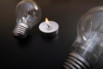 Electric lamp and candle on a dark background.  Incandescent bulb and candle. Power cut or power...