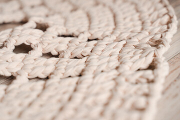 Crocheted carpet made of beige color noodle yarn, close-up