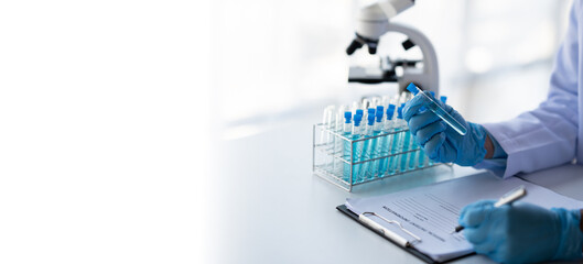 biochemical research scientist working with microscope for vaccine development in pharmaceutical...