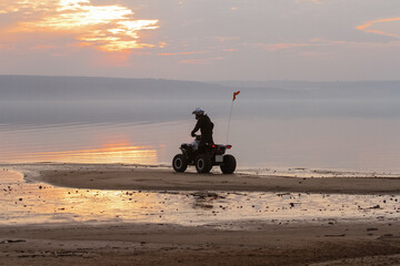 athlete rides a quad bike on the beach at the sunset © Елена Вырыпаева