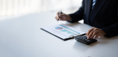 Close up view of professional businessman estimate the company budget, using calculator in the office room.