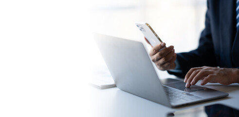 Businessman working for his project while using smartphone and laptop computer at the same time in the office room.