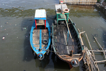 portrait of traditional fishing boats on a dirty river