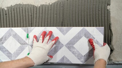 Instaling ceramic tiles. Male hands glue ceramic tiles on the wall in the bathroom.