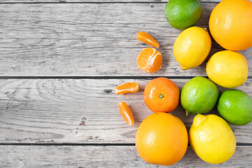 Yellow, orange and green citrus fruits on wooden background with blank space, top view