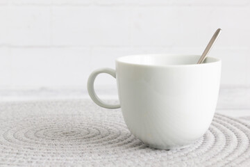 A white coffee mug with a spoon on bright background