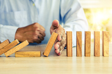 Close-up hand prevent wooden block not falling domino concepts of financial risk management and...