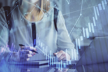 Double exposure of businesswoman hands typing on computer and financial graph hologram drawing. Stock market analysis concept.