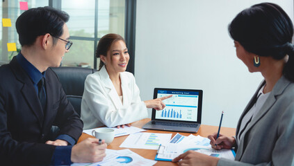 Group of Asian business people meeting about business plan and present and explain stock financial chart from laptop computer at office.