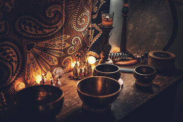 A closeup of perfumes bottles in candlelight and tibetan bowls.
