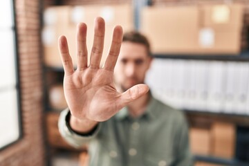 Young man ecommerce business worker doing stop gesture with hand at office - obrazy, fototapety, plakaty