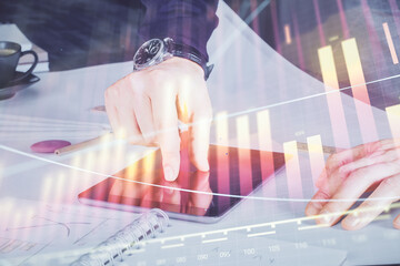 Double exposure of man's hands holding and using a digital device and forex graph drawing. Financial market concept.