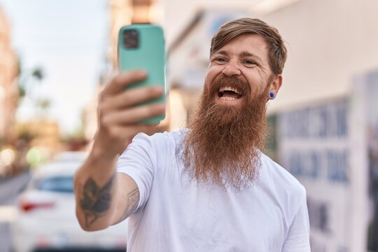 Young redhead man smiling confident making selfie by the smartphone at street