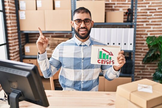 Middle East Man With Beard Working At Small Business Ecommerce Holding Crisis Banner Smiling Happy Pointing With Hand And Finger To The Side