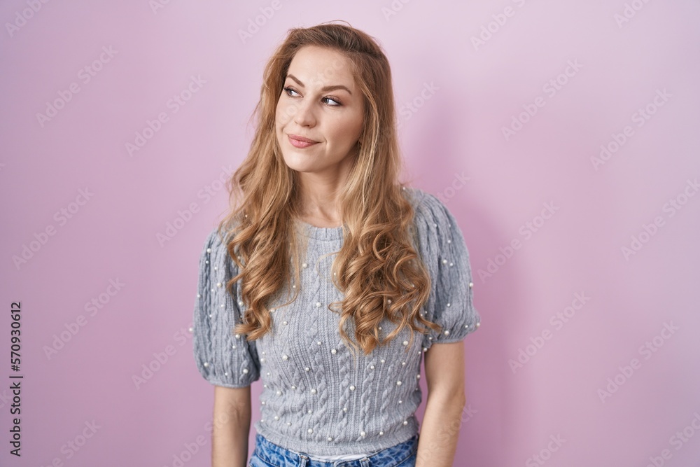 Sticker beautiful blonde woman standing over pink background smiling looking to the side and staring away th