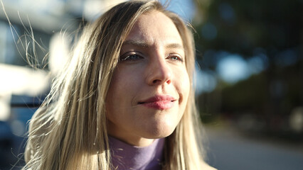Obraz premium Young blonde woman looking to the side with relaxed expression at street
