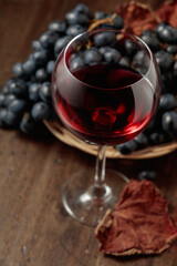 Red wine and blue grapes on an old wooden table.