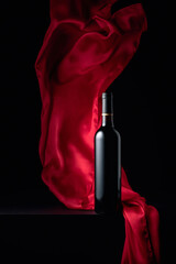Bottle of red wine and flutters of red cloth.