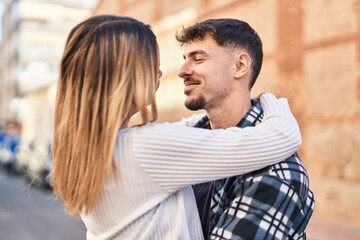 Fototapeta premium Young man and woman couple hugging each other standing at street