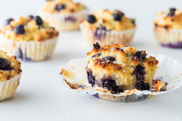 Fresh blueberry muffins with the paper liner peeled back from the one in front.