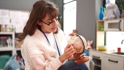 Young caucasian woman teaching with world globe at kindergarten