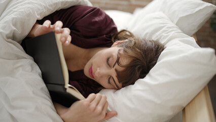 Young caucasian woman reading a book in the bed at bedroom