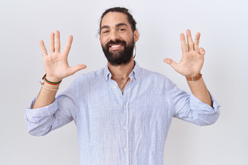 Naklejka premium Hispanic man with beard wearing casual shirt showing and pointing up with fingers number nine while smiling confident and happy.