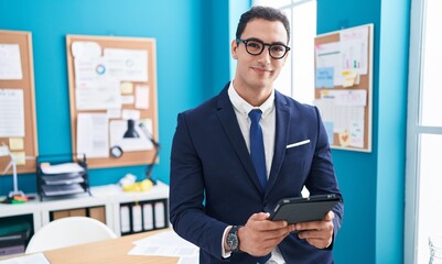 Young hispanic man business worker smiling confident using touchpad at office