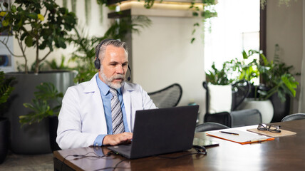 Senior caucasian doctor online video call conference consult patient with headset on laptop computer. Doctor online consultation and telehealth medicine