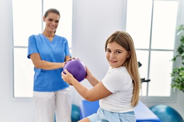Obraz premium Woman and girl physiotherapist and patient having rehab session using ball at physiotherapy clinic