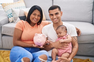 Young hispanic couple with baby holding piggy bank smiling with a happy and cool smile on face....