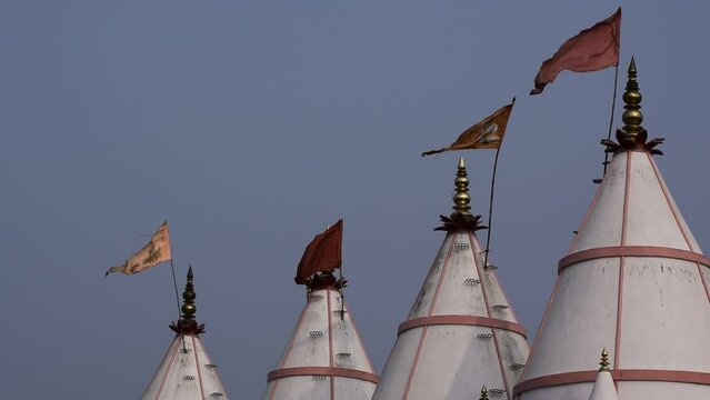 Bina, India 2022: Flags waiving in air on the top of white color temple building. Four flags can be seen waiving over the temple top 
