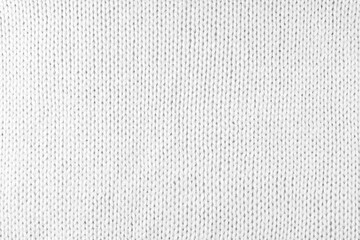 Fototapeta na wymiar Close up background of knitted wool fabric made of viscose yarn. White color wool knitwear texture. Abstract knitted jersey background. Fabric abstract backdrop, wallpaper
